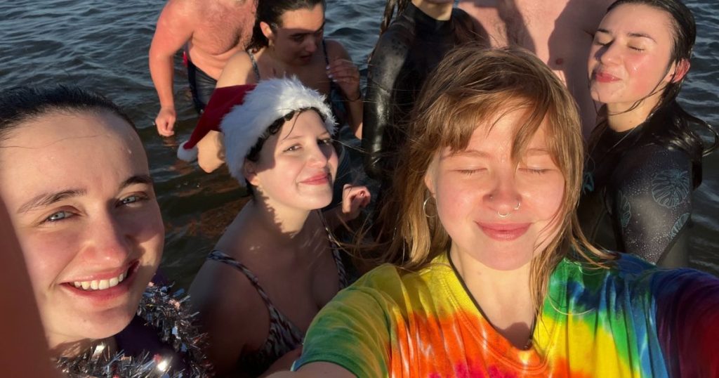 Selfie of a group of students standing in the sea and smiling at the sun