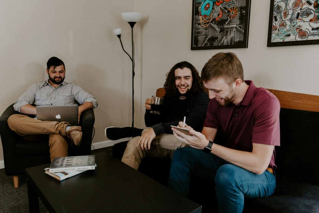 Three young men, wearing smart casual clothes sitting smiling and laughing