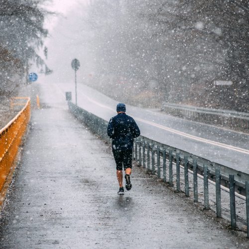 Person running next to a road in bad weather Person running next to a road in bad weather