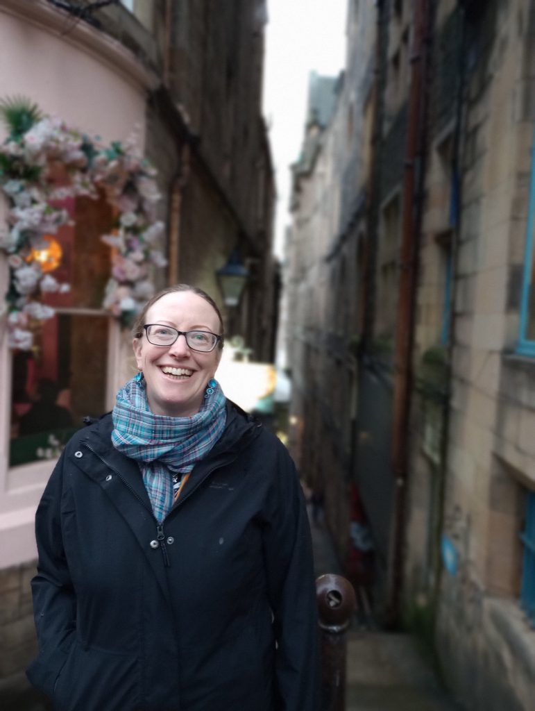 Person smiling stood at the entrance to a narrow street